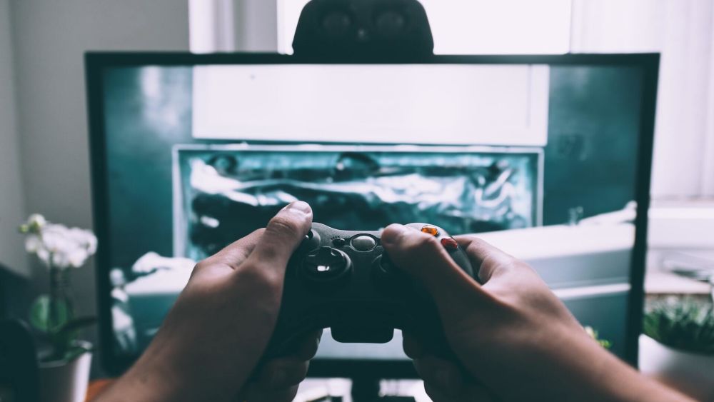 third-person view of a person holding a controller for a gaming device. 